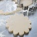 Stainless steel Ateco flower-shaped cookie cutter cutting cookie dough.