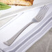 A Bon Chef stainless steel dinner fork on a plate with food.