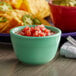 A green Tuxton China bouillon cup filled with salsa on a table.