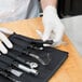 A person in white gloves using Dexter-Russell garnishing tools on a cutting board.