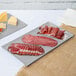 A Tablecraft natural cast aluminum rectangular cooling platter with meat and cheese on it.