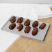 A Tablecraft natural cast aluminum rectangular cooling platter with chocolate covered donuts on a white surface.