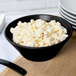 A black Tablecraft round cast aluminum bowl filled with macaroni salad.