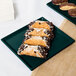 A Tablecraft hunter green rectangular cast aluminum cooling platter with pastries on it.