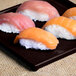 A Tablecraft midnight speckle cast aluminum rectangular cooling platter with sushi on it.