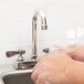 A person washing their hands in a stainless steel sink.