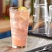 A Libbey stackable mixing glass filled with pink lemonade sits on a table.
