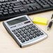 A silver and black Victor 10-digit solar calculator on a desk next to a keyboard.