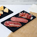 A Tablecraft midnight with blue speckle cast aluminum rectangular cooling platter with meat and cheese on it.