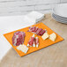 An orange Tablecraft rectangular cast aluminum cooling platter with cheese and ham on it.