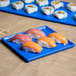 A Tablecraft blue speckle cast aluminum rectangular platter holding sushi on a table.