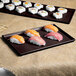 A Tablecraft midnight speckle cast aluminum rectangular cooling platter with sushi on a table.