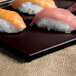 A Tablecraft midnight speckle cast aluminum rectangular cooling platter with sushi on it.