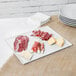 A Tablecraft white cast aluminum rectangular cooling platter with a stack of meat and cheese.