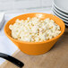 An orange Tablecraft cast aluminum serving bowl filled with macaroni salad.