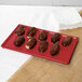 A chocolate covered donut on a red Tablecraft rectangular cooling platter.