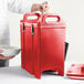 A man holding a red Cambro insulated soup carrier with a white bowl inside.