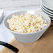 A natural cast aluminum serving bowl filled with macaroni salad with a black handle.