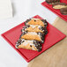 A Tablecraft red cast aluminum rectangular cooling platter with chocolate covered pastries on a table.