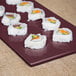 A Tablecraft maroon speckle rectangular cast aluminum cooling platter with sushi on it.