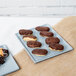 A gray Tablecraft rectangular cooling platter holding chocolate covered pastries.