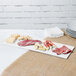 A white Tablecraft cast aluminum rectangular platter with meat and cheese on it.