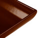 A close-up of a brown Tablecraft cast aluminum flared rectangular platter with a shiny surface.