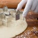 A person using a Wilton metal star cookie cutter to cut out a star-shaped cookie.