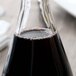 A Stolzle Pisa carafe filled with dark liquid on a table.