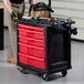 A man standing next to a Rubbermaid mobile work center with tools in it.