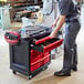 A man using a Rubbermaid Mobile Work Center with drawers to move tools.