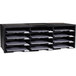A black Storex plastic literature organizer with twelve compartments on a table with white paper in some sections.