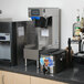 A Curtis Polaris tea brewing machine on a black counter with a metal container.