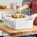 A large white polyethylene food storage box filled with potatoes on a kitchen counter.