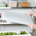 A person holding a white plastic Choice food storage container lid.