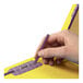 A person's hand using a pencil to write on a yellow Smead classification folder.