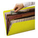 A hand putting a paper into a yellow Smead SafeSHIELD classification folder.