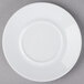 A Schonwald white porcelain saucer with a circular edge on a gray surface.