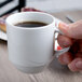 A person holding a white Schonwald Donna stacking mug filled with brown liquid.