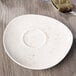 A Schonwald white porcelain saucer with brown specks next to a spoon.