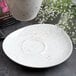A white Schonwald porcelain saucer with brown speckled spots.
