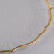 A close up of a Charge It by Jay clear glass charger plate with a gold scalloped edge.
