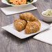 A rectangular white porcelain platter with a plate of croissants and shrimp.