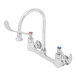 A silver T&S wall mounted surgical sink faucet with wrist action handles.