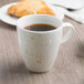 A Schonwald white porcelain cup filled with coffee on a table.