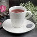A Schonwald white porcelain cup of tea on a saucer with a bag of tea.