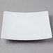 A Schonwald white porcelain square coupe plate with a white rim on a gray surface.