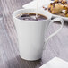 A white Schonwald porcelain cup filled with brown liquid.