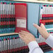 A person holding a red Smead Poly Out Guide file folder.