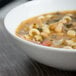 A bowl of soup with beans and vegetables in a Schonwald white porcelain bowl.